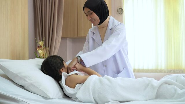 Arab doctor woman examining asian girl patient body by stethoscope on bed in hospital