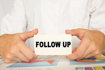 a man in the office holds a card with text FOLLOW UP. business concept