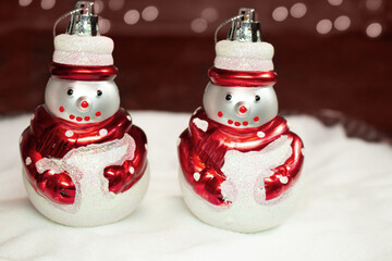 Two snowmen on the snow and red background with bokeh. Christmas and New year card