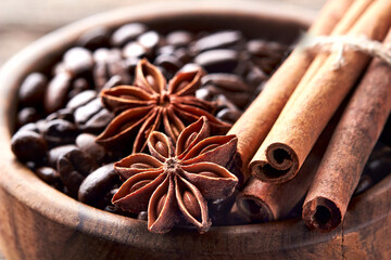 Obraz na płótnie Canvas Coffee beans, anise and cinnamon in wooden bowl on wooden background closeup.