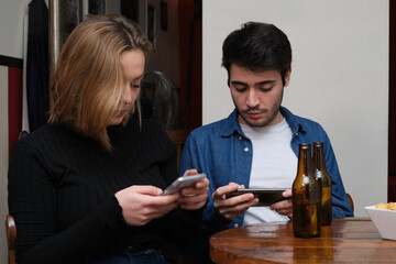 Two friends checking something on their smartphone in a pub. Friendship concept.
