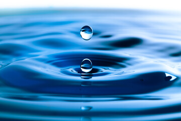 Dark blue water droplets splash in the water surface  close up. Creating a perfect water wave