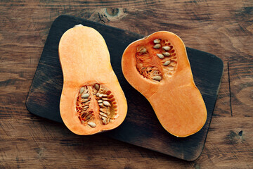 Pumpkin cut into halves on dark wooden table