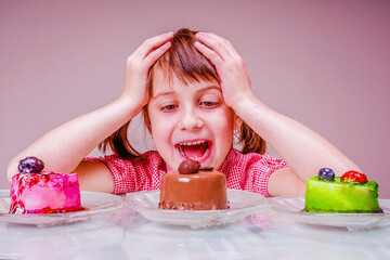 Difficult choice for young beautiful and very happy girl  which cake to eat first. Funny portrait. Holiday, sweets, pleasure, food and childhood concept. Horizontal image.