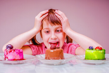 Difficult choice for young beautiful and very happy girl  which cake to eat first. Funny portrait. Holiday, sweets, pleasure, food and childhood concept