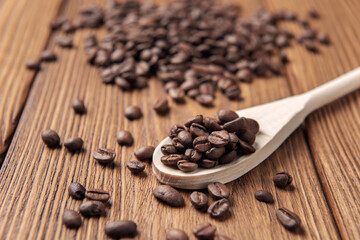 Wooden spoon with coffee grains on textured wooden table