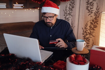 Happy man wearing Santa Claus hat holding gift or credit card