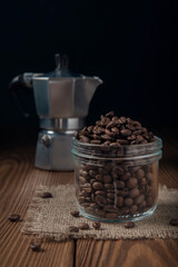 Coffee maker and glass jar with coffee beans on wooden table