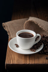 White cup with espresso and coffee beans on wooden table
