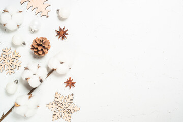 Christmas or winter composition, Cotton flowers, pine cones and wooden decorations at white table. Zero waste organic decorations. Top view with copy space.