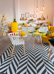 Trendy fashion luxury interior design in Scandinavian style of studio apartment with bright yellow furniture and decorated with new year lights.