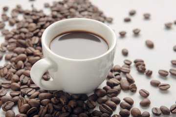 Cup of coffee with coffee beans on white background