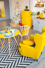 Trendy fashion luxury interior design in Scandinavian style of studio apartment with bright yellow furniture and decorated with new year lights.