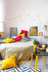 Trendy fashion luxury interior design in Scandinavian style of studio apartment with bright yellow furniture and decorated with new year lights.
