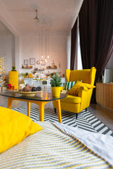 Trendy fashion luxury interior design in Scandinavian style of studio apartment with bright yellow furniture and decorated with new year lights.