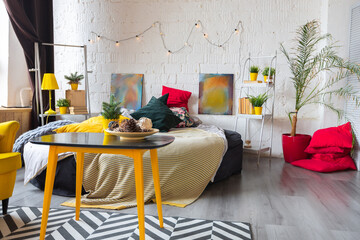 Trendy fashion luxury interior design in Scandinavian style of studio apartment with bright yellow furniture and decorated with new year lights.