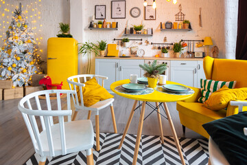 Trendy fashion luxury interior design in Scandinavian style of studio apartment with bright yellow furniture and decorated with new year lights.