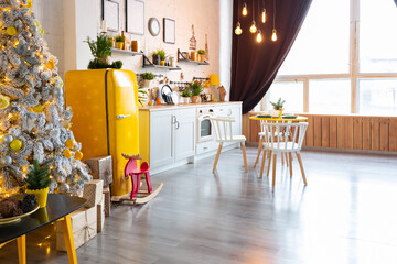 Trendy fashion luxury interior design in Scandinavian style of studio apartment with bright yellow furniture and decorated with new year lights.