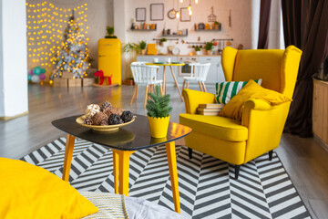 Trendy fashion luxury interior design in Scandinavian style of studio apartment with bright yellow furniture and decorated with new year lights.