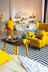 Trendy fashion luxury interior design in Scandinavian style of studio apartment with bright yellow furniture and decorated with new year lights.