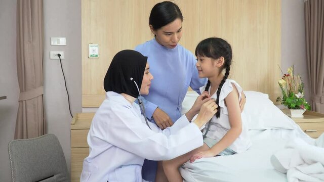 Arab doctor woman examining asian girl patient body by stethoscope on bed with mather  in hospital