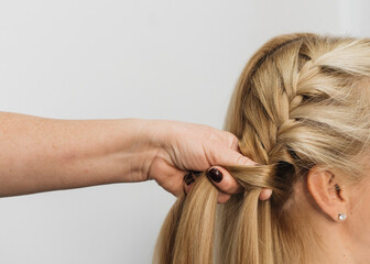 Girl in a hair salon, stylist make hair style for client in Woman's Hair In Hairdresser Salon, close view of hands, spikelet 