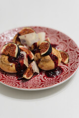 Cottage cheese pancakes with strawberry jam, figs and cheese slices in plate on table