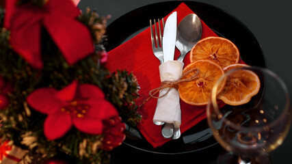 Setting for festive Christmas dinner on black table with New year decoration and dry oranges