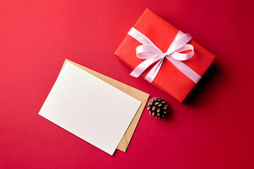 Greeting card mockup with gift box and pine cone on red background
