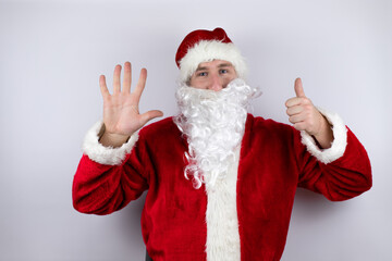 Fototapeta na wymiar Man dressed as Santa Claus standing over isolated white background showing and pointing up with fingers number six while smiling confident and happy
