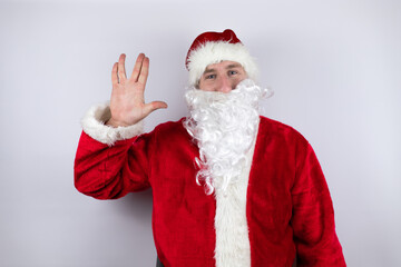 Fototapeta na wymiar Man dressed as Santa Claus standing over isolated white background doing star trek freak symbol