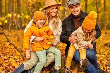 family have spare time in autumn park or forest, happily laughing smiling, wearing warm coats, sit surrounded by autumn leaves and trees. portrait