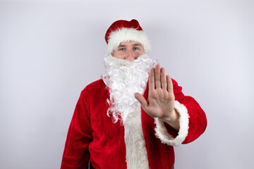 Man dressed as Santa Claus standing over isolated white background serious and doing stop sing with palm of the hand.