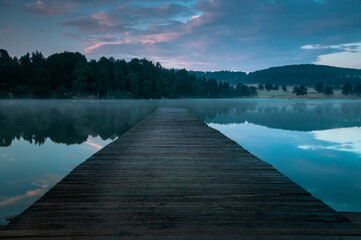 wooden jetty on lake at sunrise.
