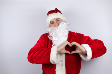 Man dressed as Santa Claus standing over isolated white background smiling in love showing heart symbol and shape with hands