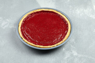 Strawberry pie in baking dish on grey concrete background.