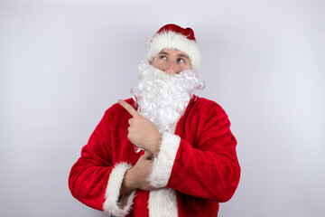 Man dressed as Santa Claus standing over isolated white background smiling happy pointing with hand and finger to the side