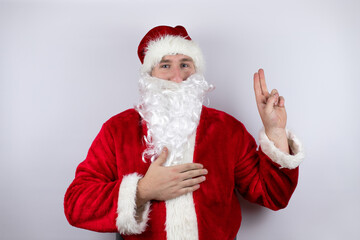 Man dressed as Santa Claus standing over isolated white background smiling swearing with hand on chest and fingers up, making a loyalty promise oath