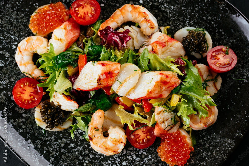 Wall mural salad with shrimp, vegetables and crab meat on a black backgroun