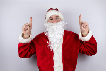 Fototapeta na wymiar Man dressed as Santa Claus standing over isolated white background pointing up