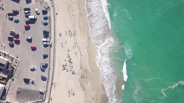 Vehicles Parked At Portreath Car Park - Sea Front Parking Lot With People On Portreath Beach, Redruth, England, UK.  -aerial top down