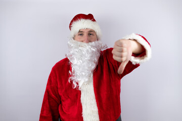 Fototapeta na wymiar Man dressed as Santa Claus standing over isolated white background with angry face, negative sign showing dislike with thumb down