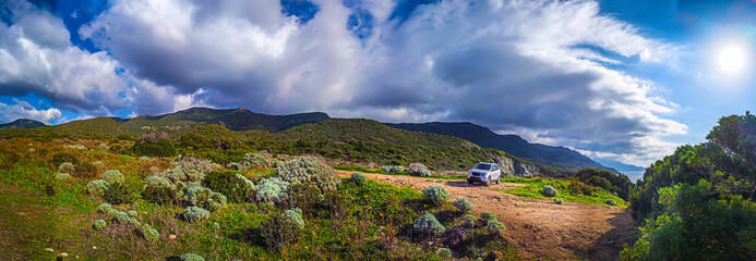 Grey SUV parked in the Sardinian countryside under a cloudy sky