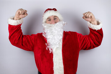 Fototapeta na wymiar Man dressed as Santa Claus standing over isolated white background very happy and excited making winner gesture with raised arms, smiling and screaming for success.