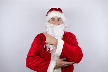 Fototapeta na wymiar Man dressed as Santa Claus standing over isolated white background smiling confident pointing with hand and finger to the side