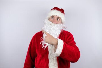 Man dressed as Santa Claus standing over isolated white background pointing with hand and finger to the side surprised