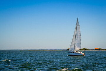 Fototapeta premium Yacht boat in the blue sea in front of the sand dune in Bassin d'arcachon 