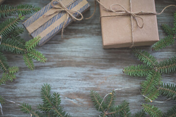 Christmas background. Gift boxes wrapped in craft paper, fir branches and garland lights.