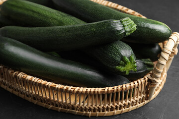 Basket with green zucchinis on black slate table, closeup