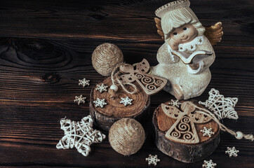Figurine of an angel, wooden cuts, snowflakes, stars, balls in a rustic style on a wooden background. Christmas composition.